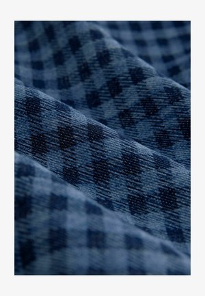 Mėlynų atspalvių tekstūruota medžiaga su skirtingo dydžio languotu raštu, suteikiančiu gylio ir vizualinio patrauklumo. Minkšta, austinė medžiaga.