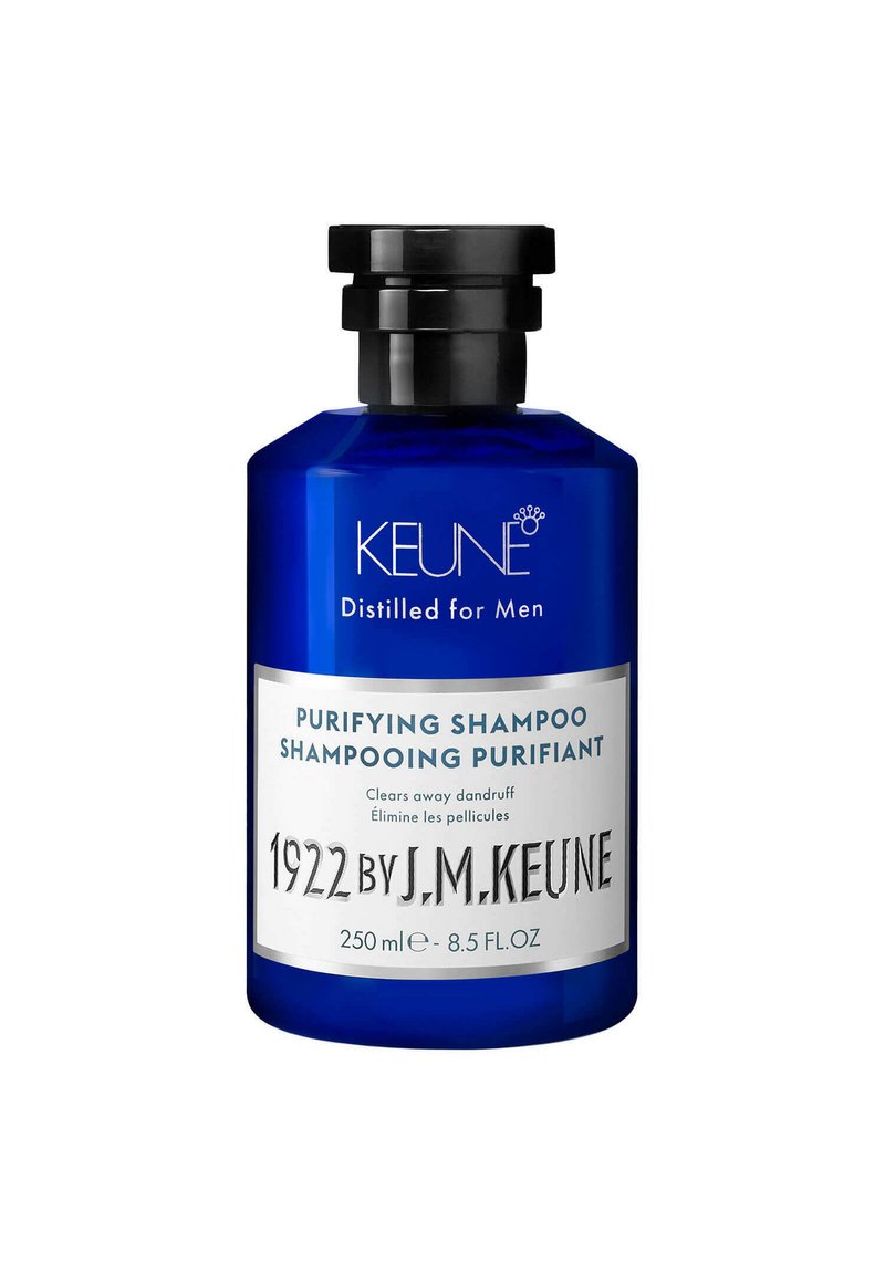 Bouteille en verre bleu avec un bouchon à vis noir. L'étiquette présente un texte blanc détaillant le produit : "Shampoing Purifiant" et le nom de la marque "KEUNE." Taille de 250 ml.