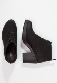 Svarta ankelstövlar med en texturerad yta, snörningsdesign och en kraftig klack. Har rund tå och förstärkt gummisula för bra grepp.