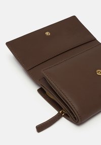 Brown leather wallet with a smooth texture, featuring a snap closure and zipper pocket. Gold hardware accents complete the design.