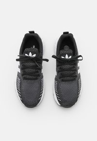 Scarpe da ginnastica nere con parte superiore in maglia testurizzata, dettagli bianchi e design a tre strisce. Presentano lacci neri e una suola ammortizzata.
