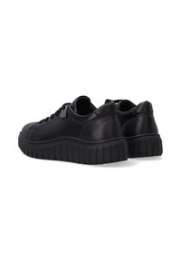 Schwarze Leder-Sneaker mit einer dicken, strukturierten Gummisohle, runder Zehenpartie, Schnürverschluss und gepolstertem Kragen. Minimalistisches Design ohne sichtbare Markenkennzeichnung.