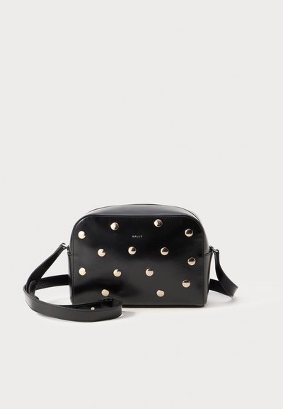 Sac à bandoulière en cuir noir avec des clous ronds en métal doré et une bandoulière réglable. Forme ronde avec une finition lisse et un détail logo sur le devant.
