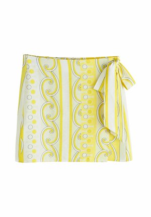 Žltá a biela zavinovacia sukňa s vertikálnymi pruhmi, vzorom špirál a bodiek, zviazaná mašľou na pravej strane