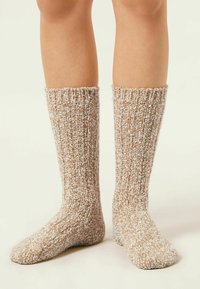 Calcetines hasta la rodilla en hilo texturizado marrón y crema con un diseño acanalado, que presentan un acabado de punto acogedor y un ajuste cómodo.