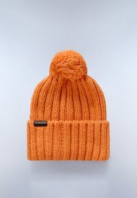 Berretto arancione lavorato a maglia con un design a coste testurizzato, dotato di un pompon rotondo sulla parte superiore e di una piccola etichetta nera sul risvolto.