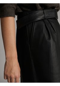 Sort lædernederdel med et bredt bælte, der har plisseringer og en glat tekstur. Fokus er på taljen og detaljer på siden.