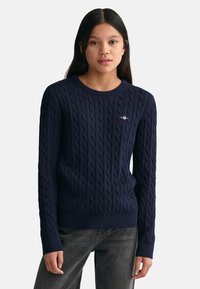 Maglione azzurro navy a maglia intrecciata con scollatura rotonda e polsini a costine, dotato di un piccolo logo sulla parte superiore sinistra del petto.