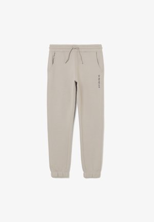 Pantalones jogger beige claro con cinturilla y puños elásticos, cordón, bolsillos laterales y la frase "LA NIEVE DEBE CONTINUAR" impresa en el muslo izquierdo.