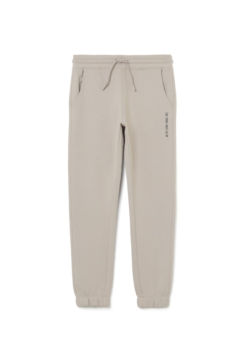 Pantalones jogger beige claro con cinturilla y puños elásticos, cordón, bolsillos laterales y la frase "LA NIEVE DEBE CONTINUAR" impresa en el muslo izquierdo.