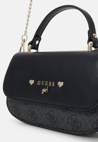 Svart syntetisk skinnveske med gullfarget detaljer, preget GUESS-logo, hjerteakenter og en avtagbar kjede-rem.
