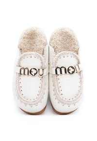 Pantofole bianche in stile mocassino con cuciture beige, foderate in soffice pile e con loghi metallici "mou" sopra, viste dall'alto.