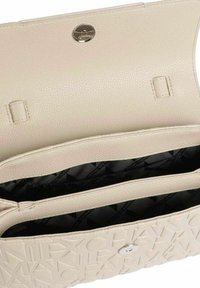 Borsa in pelle testurizzata di un beige chiaro, con una parte frontale decorata con logo in rilievo e chiusura a scatto in tonalità argentata. All'interno presenta due scomparti.