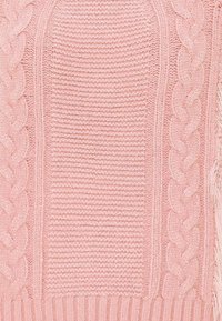 Maglione rosa lavorato a maglia con motivi a coste e a treccia, con una finitura testurizzata e un morbido dettaglio in pelliccia lungo l'orlo.