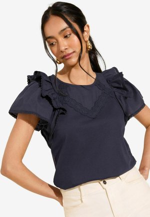 Navy blue top with short ruffled sleeves and lace trim along the neckline, paired with cream-colored bottoms. Smooth, soft texture.