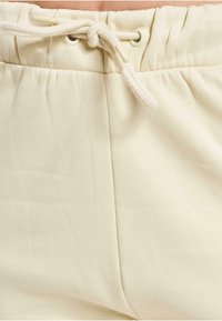 Hellebeige Sweatpants aus weichem Stoff, mit einem elastischen Bund und einer Kordel, sowie seitlichen Nähten. Keine sichtbaren Taschen.