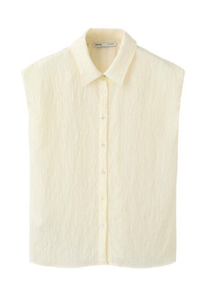 Blusa sin mangas de color crema con tejido texturizado, cuello puntiagudo y cierre frontal con botones.