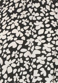 Černá látka s bílým květinovým vzorem, obsahující různé tvary a velikosti květin, hladká textura a mírný lesk.