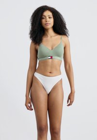 Groene katoenen bralette met dunne banden en logoband, gecombineerd met witte hooggesneden slips. Eenvoudig ontwerp, zachte textuur en aansluitende pasvorm.