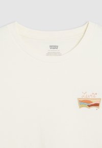 Vit bomulls-T-shirt med rund halsringning och en flerfärgad broderad Levi's-logotyp på vänstra bröstet. Slät textur.