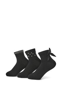 Zestaw czarnych skarpetek ankle z dekoracyjnymi akcentami: jedna z dżetami, jedna z perłowymi ozdobami, a jedna z kokardką.