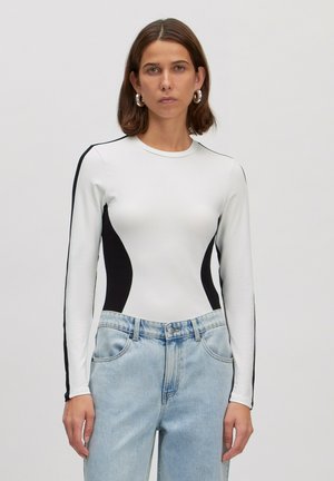 Witte lange mouwen bodysuit met zwarte zijkanten, ronde halslijn en rekbare stof. Gecombineerd met lichtgewassen denim broek.