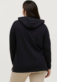 Sort langærmet hoodie med snoretræk i hætten, der har en afslappet pasform og sidesplitter i kanten for lettere bevægelse.