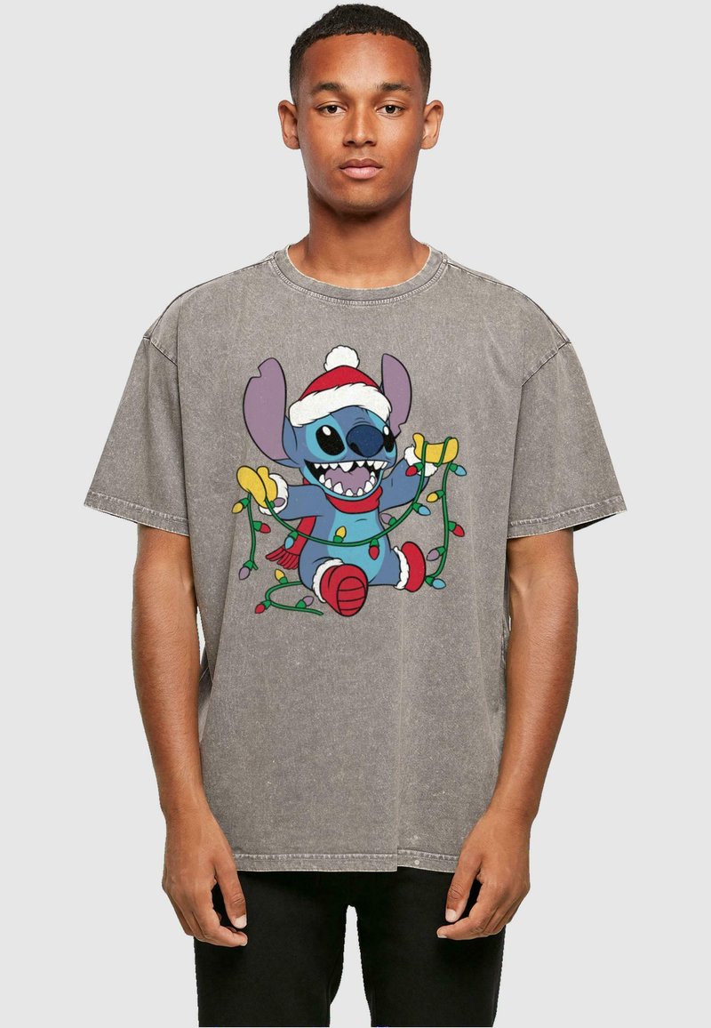 La camiseta gris de gran tamaño presenta un diseño de caricatura colorido de un personaje con un gorro de Santa y luces navideñas. Estilo clásico de cuello redondo.