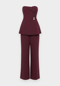 Top peplum bordeaux com design sem alças, apresentando um decote assimétrico e um detalhe decorativo dourado. Combinado com calças de perna larga.