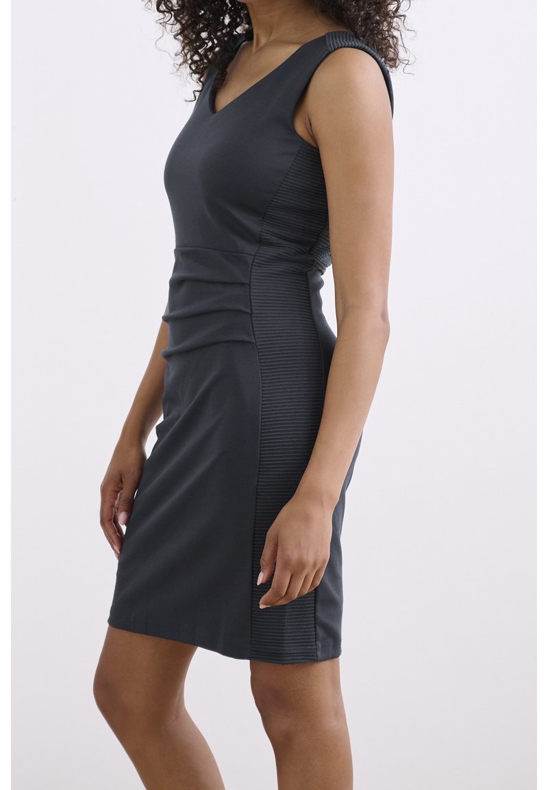 Robe grise sans manches avec un décolleté en V. Présente des panneaux texturés sur les côtés et des fronces à la taille pour une silhouette ajustée.