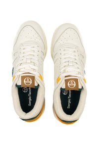 Baltā ādas sporta apavi ar perforētiem elementiem, dzelteniem un zaļiem akcentiem, kā arī fakturētu zoli. Iekļauta logo uz mēles un iekšējās zoles.