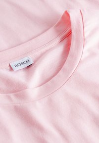Ljusrosa bomullströja med rund halsringning, med en mjuk textur och etiketten "RÖSCH" broderad nära kragen.