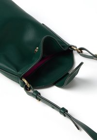 Borsa a tracolla in pelle verde scuro aperta, che mostra l'interno in tessuto bordeaux e la tracolla regolabile con hardware dorato su sfondo bianco.
