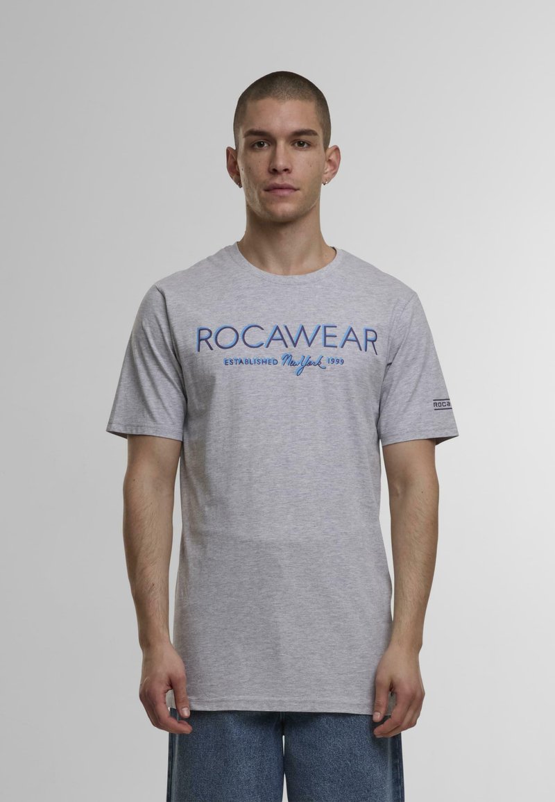 Grå bomulds t-shirt med blå ROCAWEAR-logo og etableringsdato. Korte ærmer, rund hals, lige kant og standard pasform.