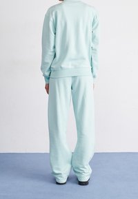 Felpa oversized azzurra chiara con pantaloni abbinati. Caratterizzata da tessuto morbido, vestibilità rilassata e polsini a coste. Design semplice senza motivi.
