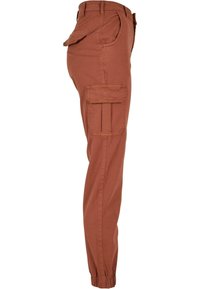 Pantalon cargo couleur rouille avec poignets élastiques, poche latérale à rabat et poches avant sur les hanches, montré en vue latérale.