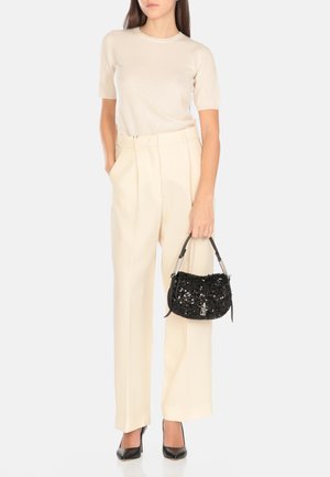 Top beige a maniche corte, pantaloni a vita alta color crema, borsa nera con paillettes e hardware argentato, e décolleté neri a punta.