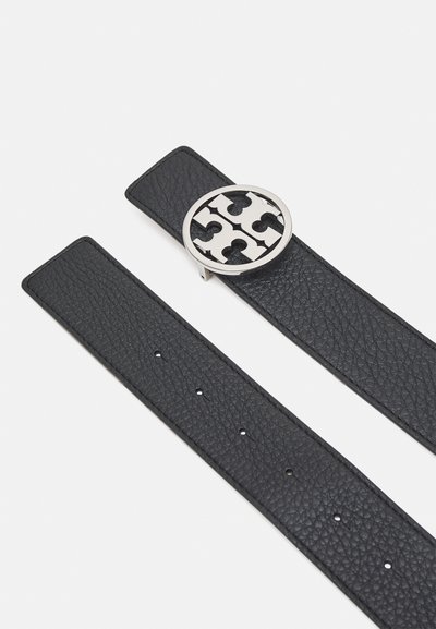 Svart läderrem med en texturerad yta, prydd med en rund spänne i silverton med geometrisk utskärningsdesign.