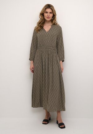 Maxikleid mit V-Ausschnitt, langen Ärmeln und elastischem Bund. Hat ein geometrisches Muster in erdigen Tönen. Kombiniert mit schwarzen Blockabsatzsandalen.