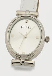 Ασημένιο ρολόι Guess με λευκό δερμάτινο λουράκι, μινιμαλιστικό καντράν, ασημένιους δείκτες ώρας και ασημένια δείκτες που δείχνουν 11:07:41.