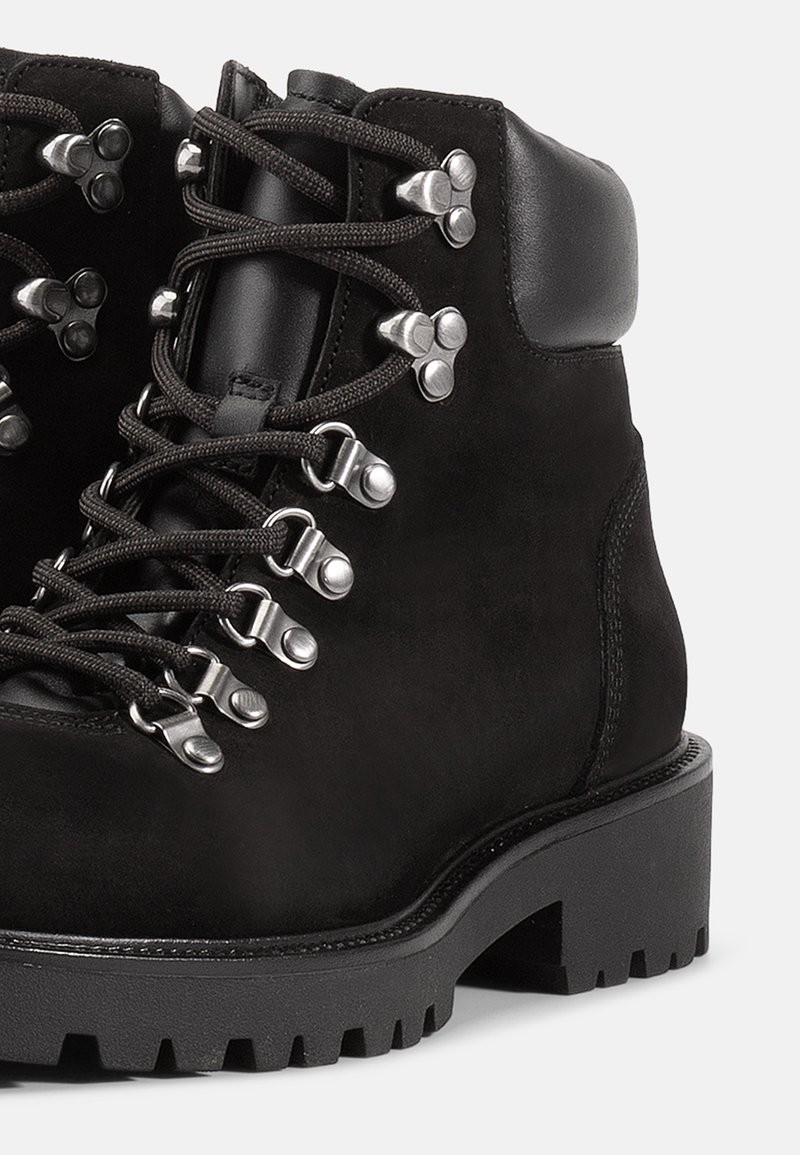 Zwarte wandelschoenen met een gestructureerde suède bovenkant, metalen oogjes en stevige veters. Dikke rubberen zool met profiel voor grip.