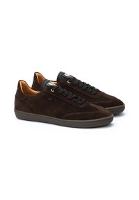 Zapatillas de ante marrón con cordones negros, suelas de goma y forro interior naranja. Presentan perforaciones sutiles y detalles de costura en contraste.