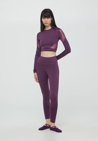 Set di activewear viola composto da un top cropped a maniche lunghe con pannelli trasparenti e leggings a vita alta con un accento in stampa leopardata.
