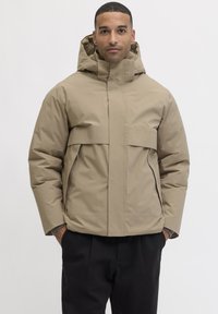 Beige Kapuzenjacke mit durchgehendem Reißverschluss, gro�ßer Brusttasche und Seitentaschen. Hergestellt aus glattem, wasserabweisendem Material mit kastiger Passform.