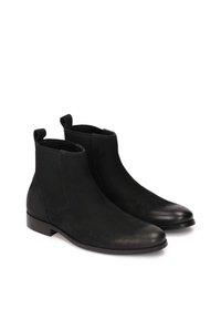 Botas de tobillo de cuero negro con paneles laterales elásticos, punteras redondeadas y tiradores. Acabado suave con un ligero brillo y un tacón bajo y plano.