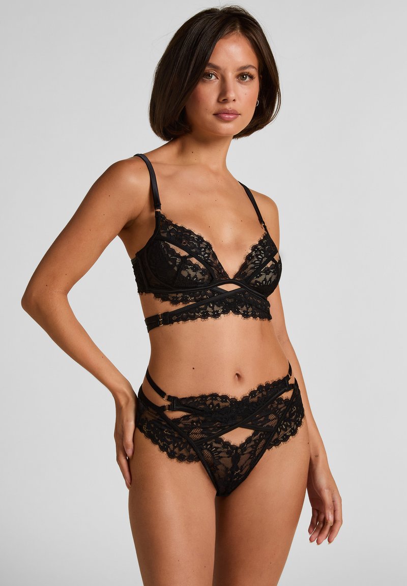 Schwarzes Spitzen-Dessous-Set mit semi-transparentem Bralette mit V-Ausschnitt und verstellbaren Trägern, ergänzt durch passende Hipster-Slips mit Cut-out-Details.