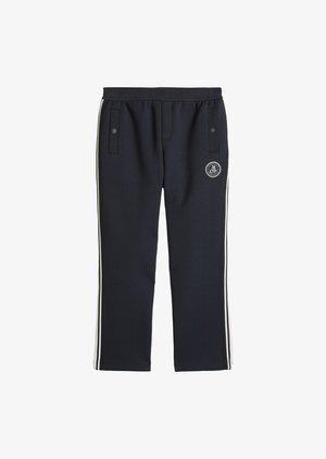 Pantalon de survêtement noir avec bandes blanches sur les côtés, taille élastique, deux poches avant à boutons-pression, et un logo circulaire MOP sur la cuisse droite.