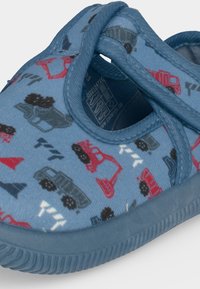 Chaussure enfant bleue avec une bande Velcro et un motif de véhicules de chantier, cônes de signalisation et panneaux routiers en rouge, noir et blanc.
