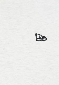 White fabric with a subtle texture, featuring a small black embroidered logo resembling a stylized letter at the center.