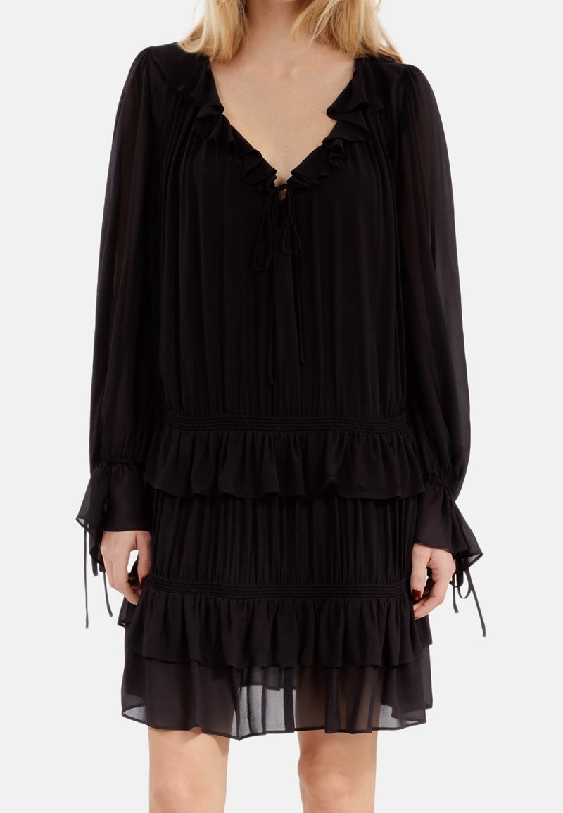 Vestido negro con volantes hecho de una tela ligera. Presenta un escote en V profundo, mangas largas con lazos y un diseño en capas con pliegues horizontales.